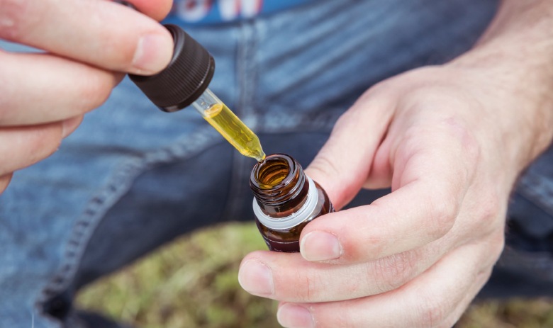 Frasco de aceite de CBD legal con pipeta sobre una superficie de madera clara
