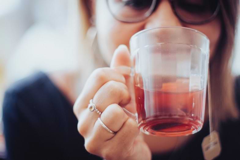 Taza de infusión de cáñamo con hojas de cannabis sativa sobre fondo claro