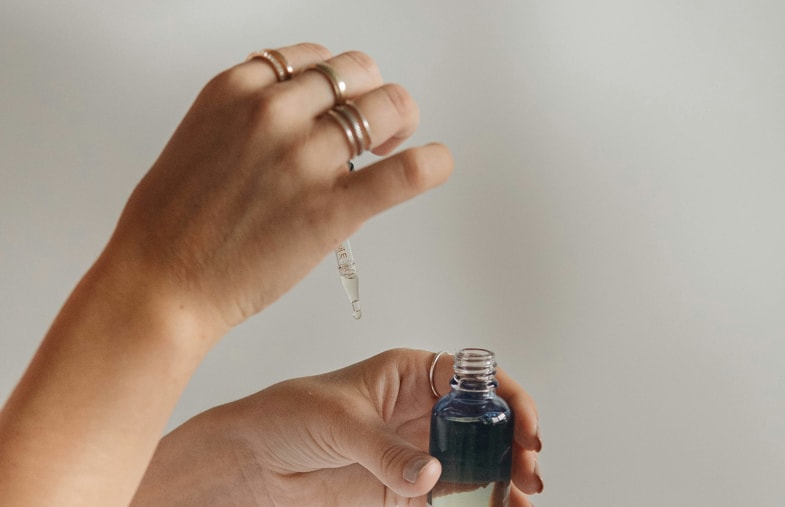 Mujer a punto de tomar aceite de CBD por vía sublingual | Justbobshop