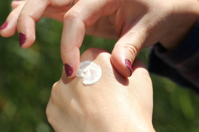 Chica untándose crema de CBD en la mano | Justbobshop
