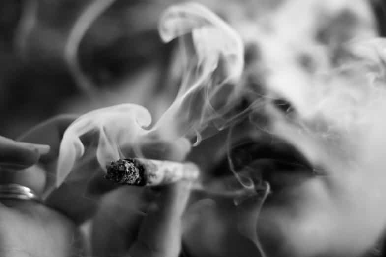 Escena con hojas de cannabis y humo en un entorno difuminado