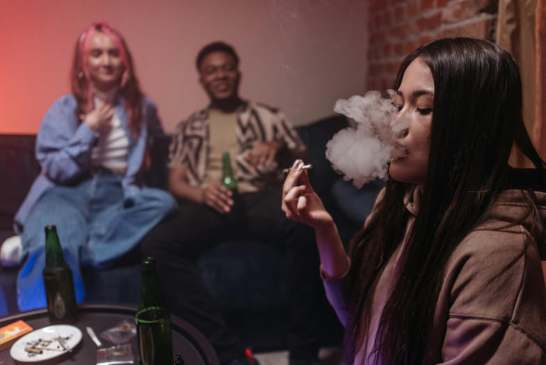 dos chicas y un chico fumando cannabis en casa