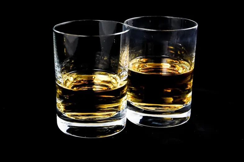 Dos vasos de whisky sobre una mesa oscura como representación del consumo de alcohol
